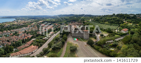 Padenghe Castle entrance, access roads and olive groves seen in a drone panorama 141611729