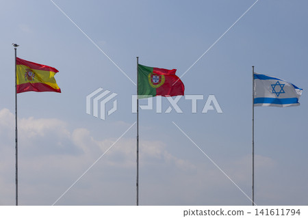 Flags of Spain, Portugal and Israel aligned above a soft bank of clouds Flags of Spain, Portugal and Israel aligned above a soft bank of clouds 141611794