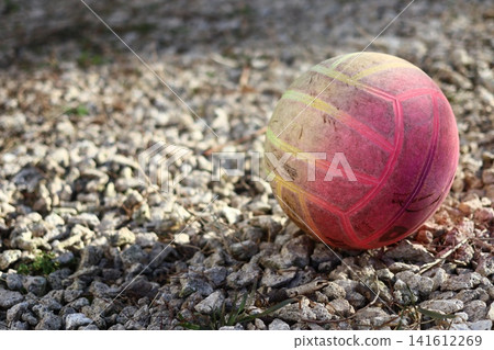A volleyball ball is lying on a gravel surface. A volleyball ball is lying on a gravel surface. 141612269