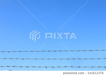 Barbed wire fence over blue sky. Barbed wire fence over blue sky. 141612378