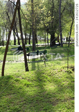 People are sitting on benches in a spring park. People are sitting on benches in a spring park. 141612726