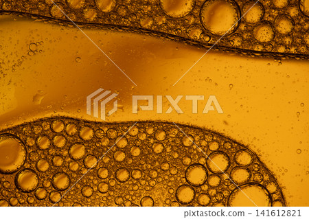 Golden liquid with oil and water separation creating tiny bubbles and abstract patterns Golden liquid with oil and water separation creating tiny bubbles and abstract patterns 141612821