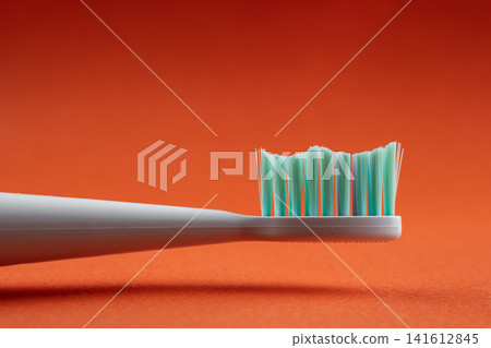 Toothbrush bristles creating wave patterns against a vibrant orange backdrop, promoting oral hygiene Toothbrush bristles creating wave patterns against a vibrant orange backdrop, promoting oral hygiene 141612845