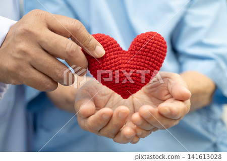 Doctor holding a red heart in hospital, healthy strong medical concept. Doctor holding a red heart in hospital, healthy strong medical concept. 141613028
