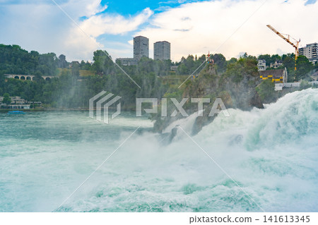 Rhine Falls Waterfall with Rapid Cascading Water and City Skyline in Neuhausen Switzerland. Powerful Water fall Stream Rhine Falls Waterfall with Rapid Cascading Water and City Skyline in Neuhausen Switzerland. Powerful Water fall Stream 141613345