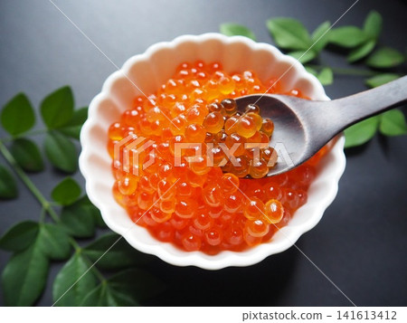 A chopstick holder for salmon roe in a white dish. A chopstick holder for salmon roe in a white dish. 141613412