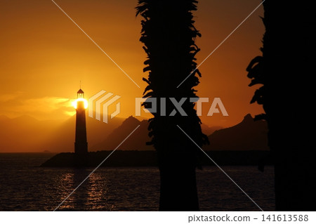 Seascape at sunshine. Lighthouse and sailings on the coast. Seaside town of Turgutreis and spectacular sunshine Seascape at sunshine. Lighthouse and sailings on the coast. Seaside town of Turgutreis and spectacular sunshine 141613588