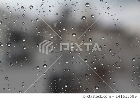 Rain drops on the glass in the spring afternoon. Close up of a window with rain drops falling down.The rain drops on household windows. Focus on rain drops. concept of sadness, frustration 141613599
