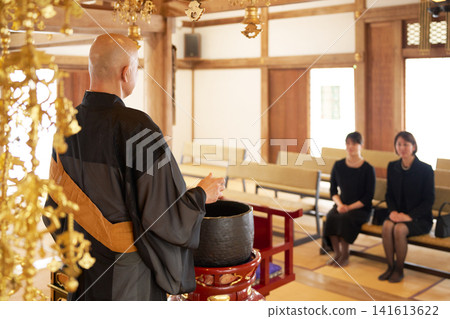 The back of a monk performing a memorial service in the main hall, and mourners in mourning attire. The back of a monk performing a memorial service in the main hall, and mourners in mourning attire. 141613622