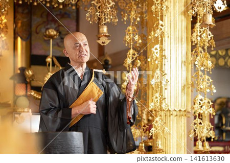 一位僧人在寺廟大殿裡講道,手中拿著念珠。 一位僧人在寺廟大殿裡講道,手中拿著念珠。 141613630