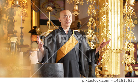 一位僧人在寺廟大殿裡講道,手中拿著念珠。 一位僧人在寺廟大殿裡講道,手中拿著念珠。 141613635
