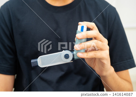 Asthma and chronic obstructive pulmonary disease COPD, Asian young man using metered dose inhaler MDI. Asthma and chronic obstructive pulmonary disease COPD, Asian young man using metered dose inhaler MDI. 141614087