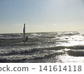 一個人在海浪的映襯下享受著帆板運動的樂趣，海浪在海面上閃閃發光。 141614118
