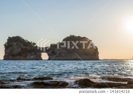A landscape of strangely shaped rocks with caves floating in the sea, bathed in the setting sun. A landscape of strangely shaped rocks with caves floating in the sea, bathed in the setting sun. 141614216