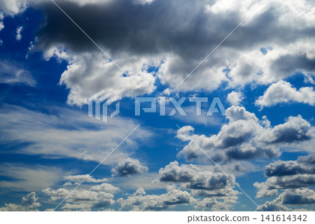 dark storm cloud at the top of the frame against cumulus clouds and blue sky dark storm cloud at the top of the frame against cumulus clouds and blue sky 141614342