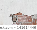 background of a damaged white plastered wall revealing red brick masonry structure 141614446