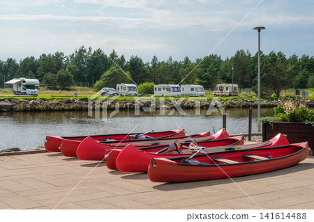 Red Canoes at Riverside Marina in Pavilosta Latvia with Camper Vans on a Peaceful Summer Day Outdoors Red Canoes at Riverside Marina in Pavilosta Latvia with Camper Vans on a Peaceful Summer Day Outdoors 141614488