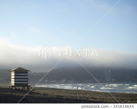 湘南風光，晨霧籠罩的海灘，沿著海岸線漫步的人們，以及海邊的小屋。 141614634
