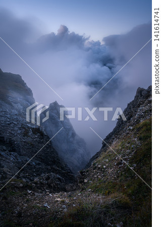 Dramatic mountain gorge with rocky cliffs in slouds Dramatic mountain gorge with rocky cliffs in slouds 141614741