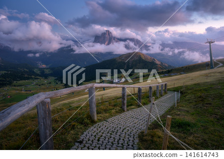 Paved walking path with wooden fence, mountains in fog at sunset Paved walking path with wooden fence, mountains in fog at sunset 141614743