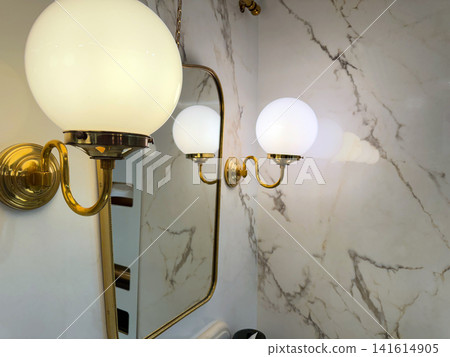 Classic brass wall light beside bathroom mirror interior Classic brass wall light beside bathroom mirror interior 141614905