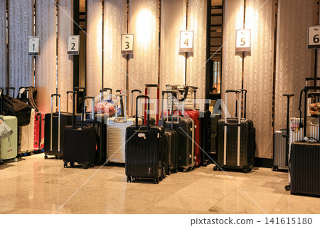 A large group of traveler's luggage organizing in a modern hotel lobby, A lot of tourist multicolored suitcases in the loading zone. A large group of traveler's luggage organizing in a modern hotel lobby, A lot of tourist multicolored suitcases in the loading zone. 141615180