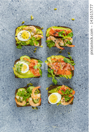 Healthy snack or appetizer toast with salmon, avocado, shrimps, eggs, cucumber, lambs lettuce or corn salad and parsley Healthy snack or appetizer toast with salmon, avocado, shrimps, eggs, cucumber, lambs lettuce or corn salad and parsley 141615777
