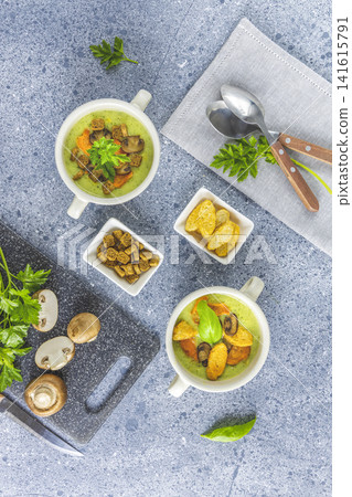 Healthy delicious vegetable soup puree with carrot chips and croutons. Served on grey table surface. Healthy delicious vegetable soup puree with carrot chips and croutons. Served on grey table surface. 141615791
