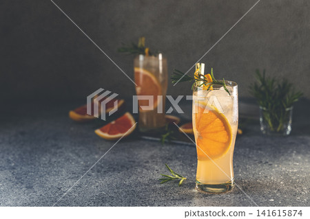 Two highball glasses of Paloma cocktails with tequila fresh grapefruit juice combined and rosemary. Dark gray concrete surface. Two highball glasses of Paloma cocktails with tequila fresh grapefruit juice combined and rosemary. Dark gray concrete surface. 141615874