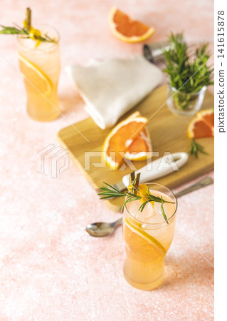 Two highball glasses of Paloma cocktails with tequila fresh grapefruit juice combined and rosemary. Surrounded of ingredients and bar tools. Light pink concrete surface. Two highball glasses of Paloma cocktails with tequila fresh grapefruit juice combined and rosemary. Surrounded of ingredients and bar tools. Light pink concrete surface. 141615878