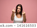 Young woman expressing anger and defiance, showing middle fingers with negative emotions, protesting against something 141616503