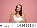 Smiling young woman giving thumbs up gesture, showing approval, success, agreement, happiness, and positivity 141616504