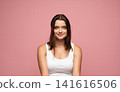 Young woman smiling with confidence, wearing a white tank top. Portrait presenting youth, beauty, and positivity on a pink background 141616506