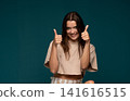 Young woman smiling and giving two thumbs up, showing approval, success, and positive support 141616515