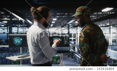 Military personnel overseeing AI computing operations on laptop in high tech server facility. Army tech experts using artificial intelligence to oversee communication systems, Military personnel overseeing AI computing operations on laptop in high tech server facility. Army tech experts using artificial intelligence to oversee communication systems, 141616864