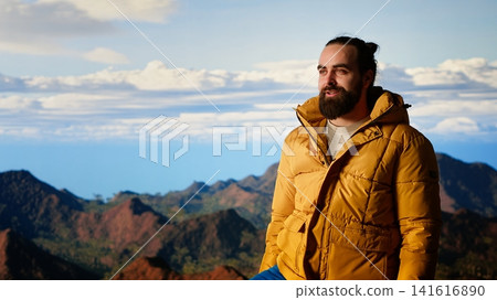 Thrilled traveler raises his arms in triumph after climbing the mountain top, enjoying the panoramic beauty of the nature. Feeling proud and admiring the vast sky and endless landscape. Camera B. Thrilled traveler raises his arms in triumph after climbing the mountain top, enjoying the panoramic beauty of the nature. Feeling proud and admiring the vast sky and endless landscape. Camera B. 141616890