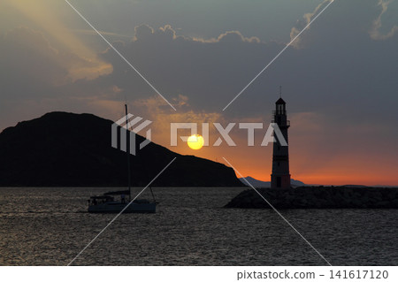 Seascape at sunshine. Lighthouse and sailings on the coast. Seaside town of Turgutreis and spectacular sunshine Seascape at sunshine. Lighthouse and sailings on the coast. Seaside town of Turgutreis and spectacular sunshine 141617120