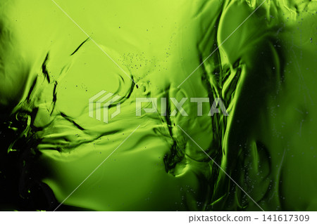 Viscous green liquid with swirling patterns creates an abstract background Viscous green liquid with swirling patterns creates an abstract background 141617309