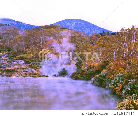 A steaming pond and mountains covered in autumn foliage. A steaming pond and mountains covered in autumn foliage. 141617414