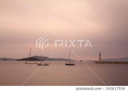 Seascape at sunshine. Lighthouse and sailings on the coast. Seaside town of Turgutreis and spectacular sunshine Seascape at sunshine. Lighthouse and sailings on the coast. Seaside town of Turgutreis and spectacular sunshine 141617554