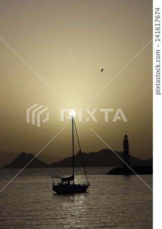 Seascape at sunshine. Lighthouse and sailings on the coast. Seaside town of Turgutreis and spectacular sunshine Seascape at sunshine. Lighthouse and sailings on the coast. Seaside town of Turgutreis and spectacular sunshine 141617674