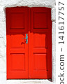 old red door next to white wall 141617757
