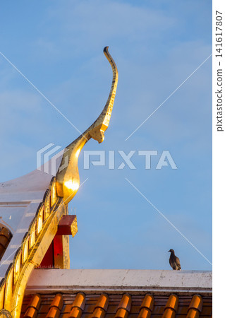 Golden temple roof detail with a bird against a clear blue sky 141617807