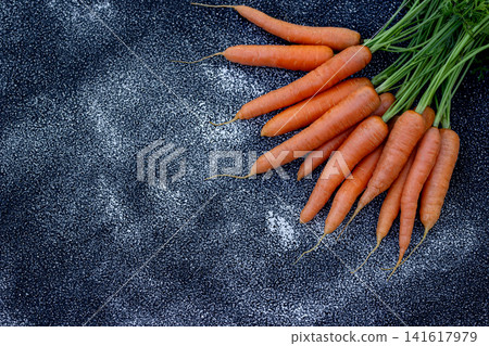Big orange organic carrots with foliage on the black background. Big orange organic carrots with foliage on the black background. 141617979