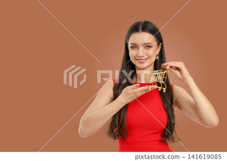 Woman in a red dress holds a golden shopping cart Woman in a red dress holds a golden shopping cart 141619085