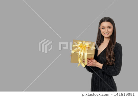 Woman with long hair poses with a golden gift box 141619091