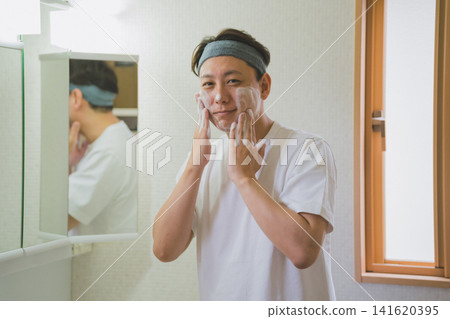 一名四十多歲的男子戴著髮帶,微笑著用雙手沾著泡沫洗臉。 一名四十多歲的男子戴著髮帶,微笑著用雙手沾著泡沫洗臉。 141620395