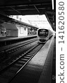 A train entering Higashi-Fushimi Station on the Seibu Shinjuku Line in Tokyo; a powerful, overhead black-and-white photograph. 141620580