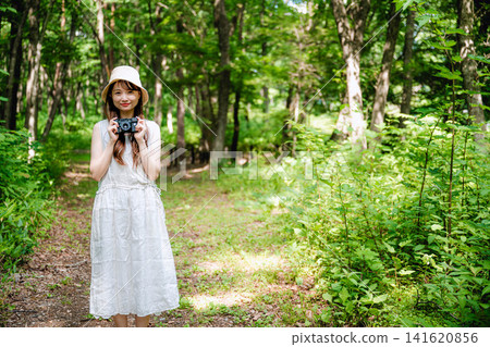 一位戴著帽子的女子走過綠色的森林。 一位戴著帽子的女子走過綠色的森林。 141620856
