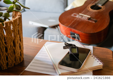 Artist preparing for music lesson, composing songs, writing sheet music with guitar, tuner, smartphone, and notebook, enjoying creative artistic process for International Music Day concept Artist preparing for music lesson, composing songs, writing sheet music with guitar, tuner, smartphone, and notebook, enjoying creative artistic process for International Music Day concept 141621866